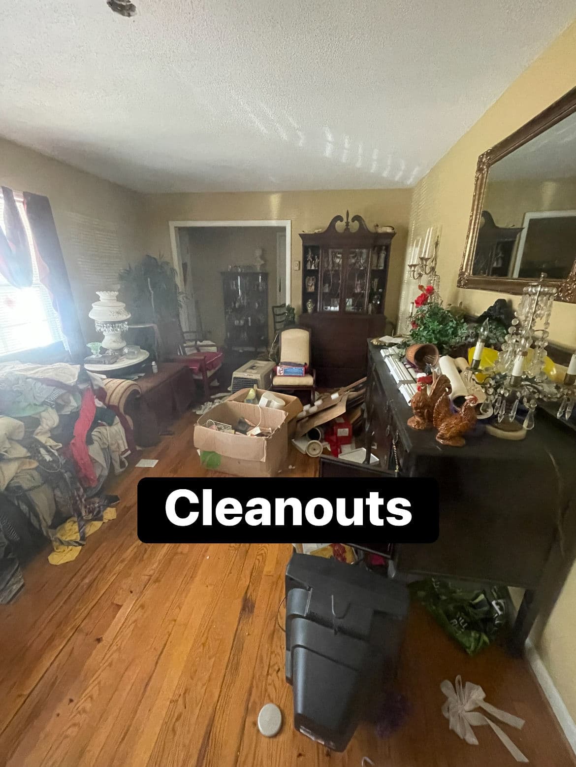 Cluttered living room during cleanout, featuring boxes and disorganized items.